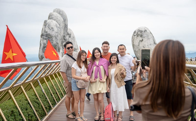 International tourists enjoy taking photos of memorabilia in Ba Na decorated with the brilliant red flag with yellow star. Photo: Thanh Son