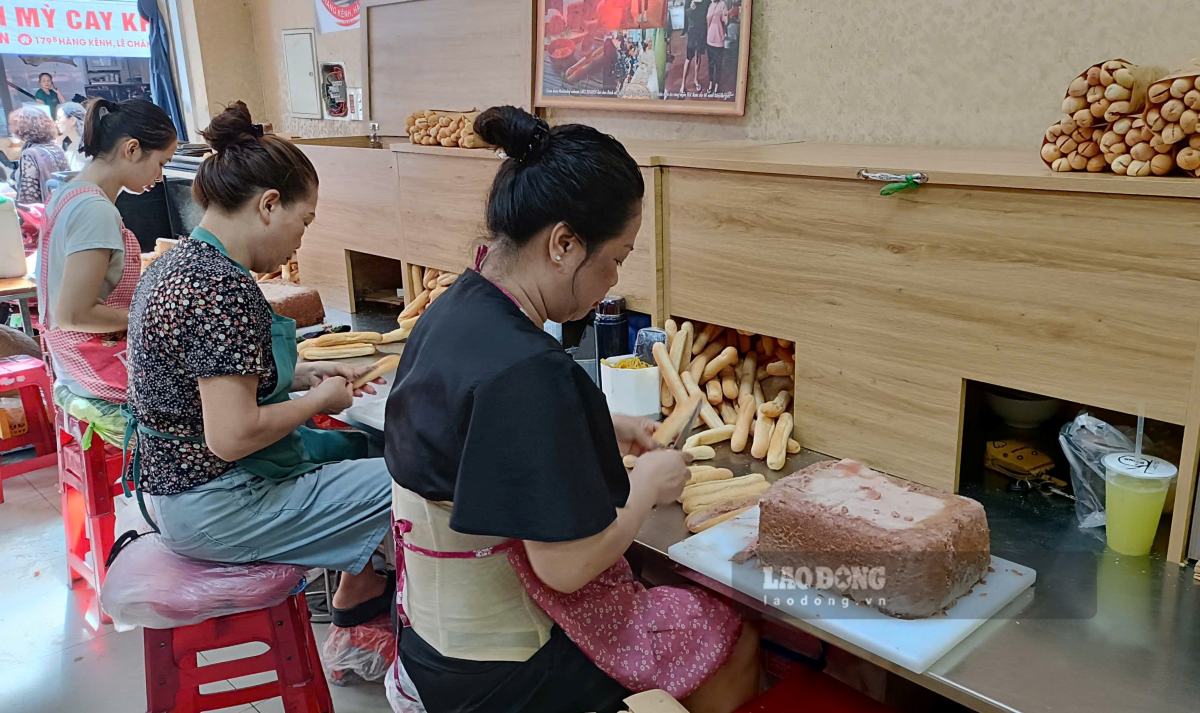 Nhan vien cua hang banh mi cay tren pho Hang Kenh lam khong nghi tay de phuc vu khach mua. Ảnh: Mai Dung