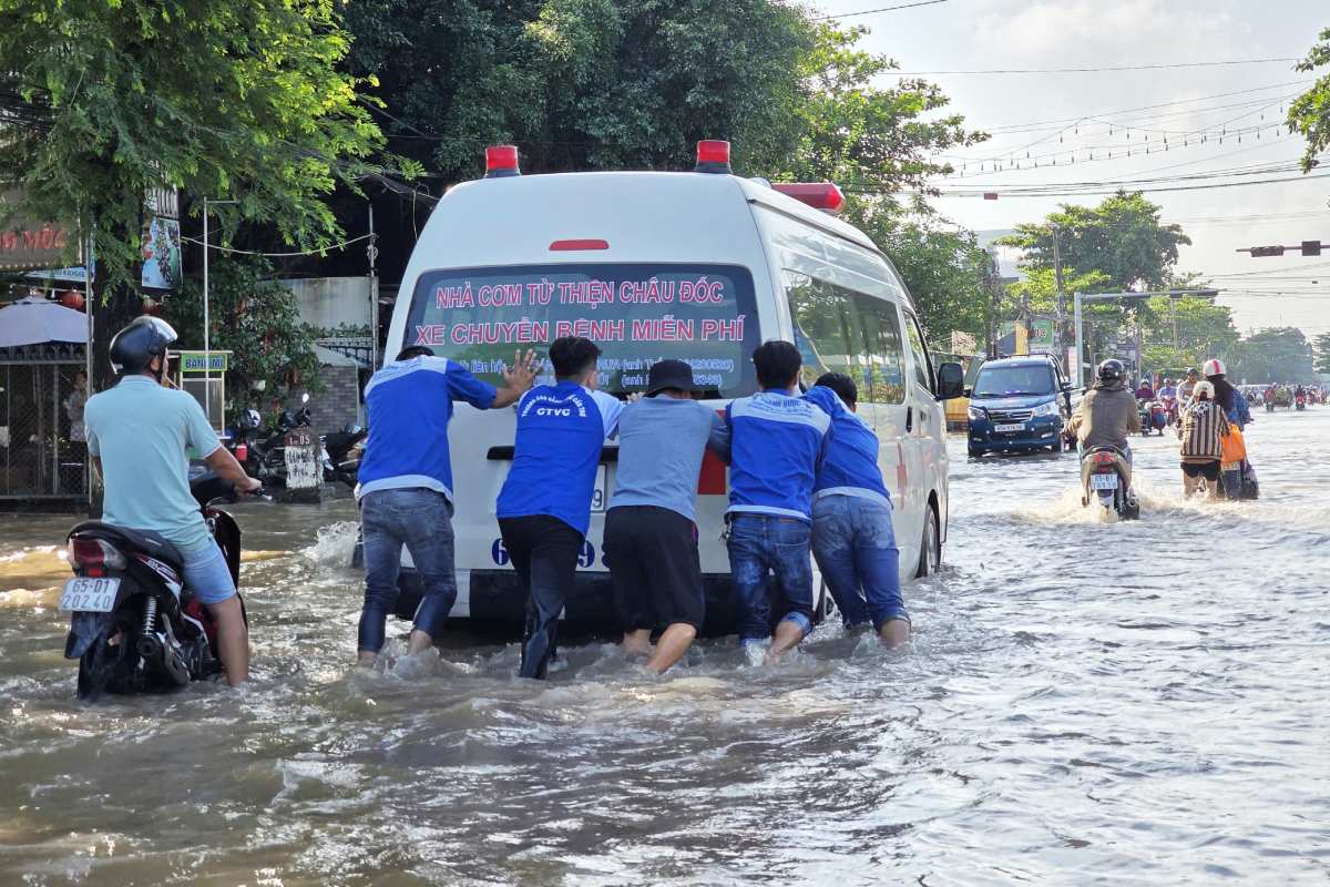 Mot chiec xe cuu thuong da phai di chuyen rat cham qua doan duong ngap, duoc nguoi dan xung quanh ho tro day qua.