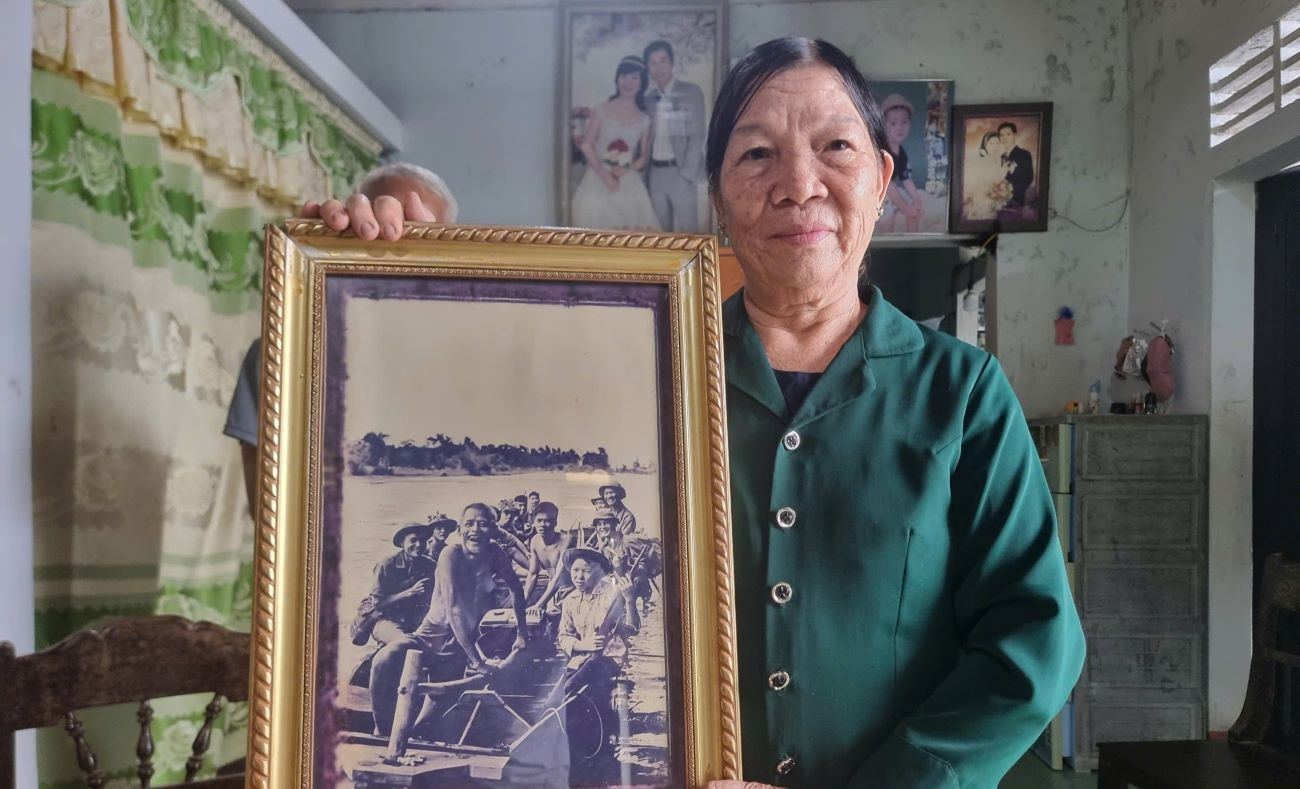 Ms. Thu with a photo of her father-in-law paddling a boat carrying soldiers across the river, taken by journalist Doan Cong Tinh at the time of the 81 days and nights of fighting to protect the ancient citadel of Quang Tri. Photo: H.Nguyen