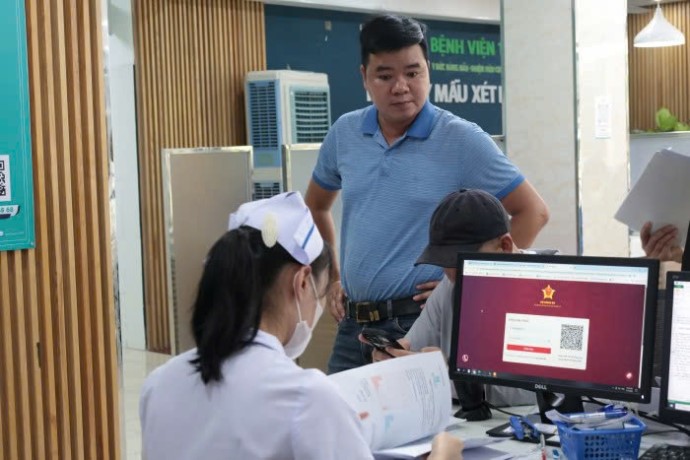 Mot nhan vien y te lam thu tuc kham, chua benh bang VNeID, can cuoc cong dan gan chip cho nguoi dan. Anh: Song Han