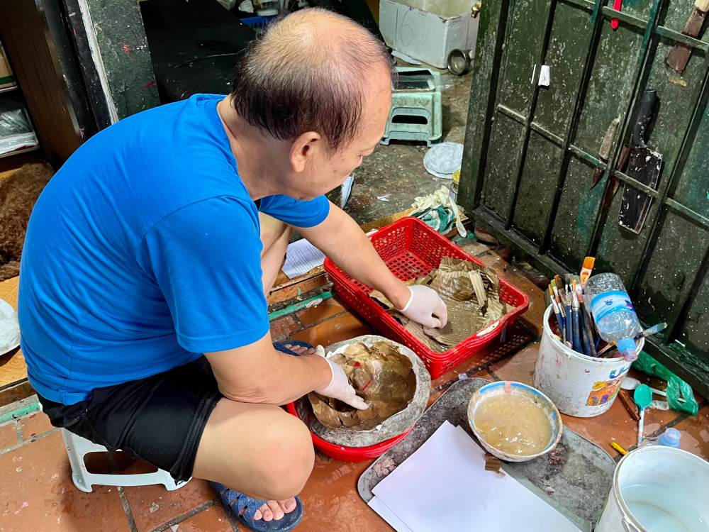 Ong Nguyen Van Hoa ti mi boi tung lop giay vao khuon de tao hinh mat na. Day la cong doan quan trong quyet dinh do ben va phom dang cua san pham. Anh: Quynh Mai