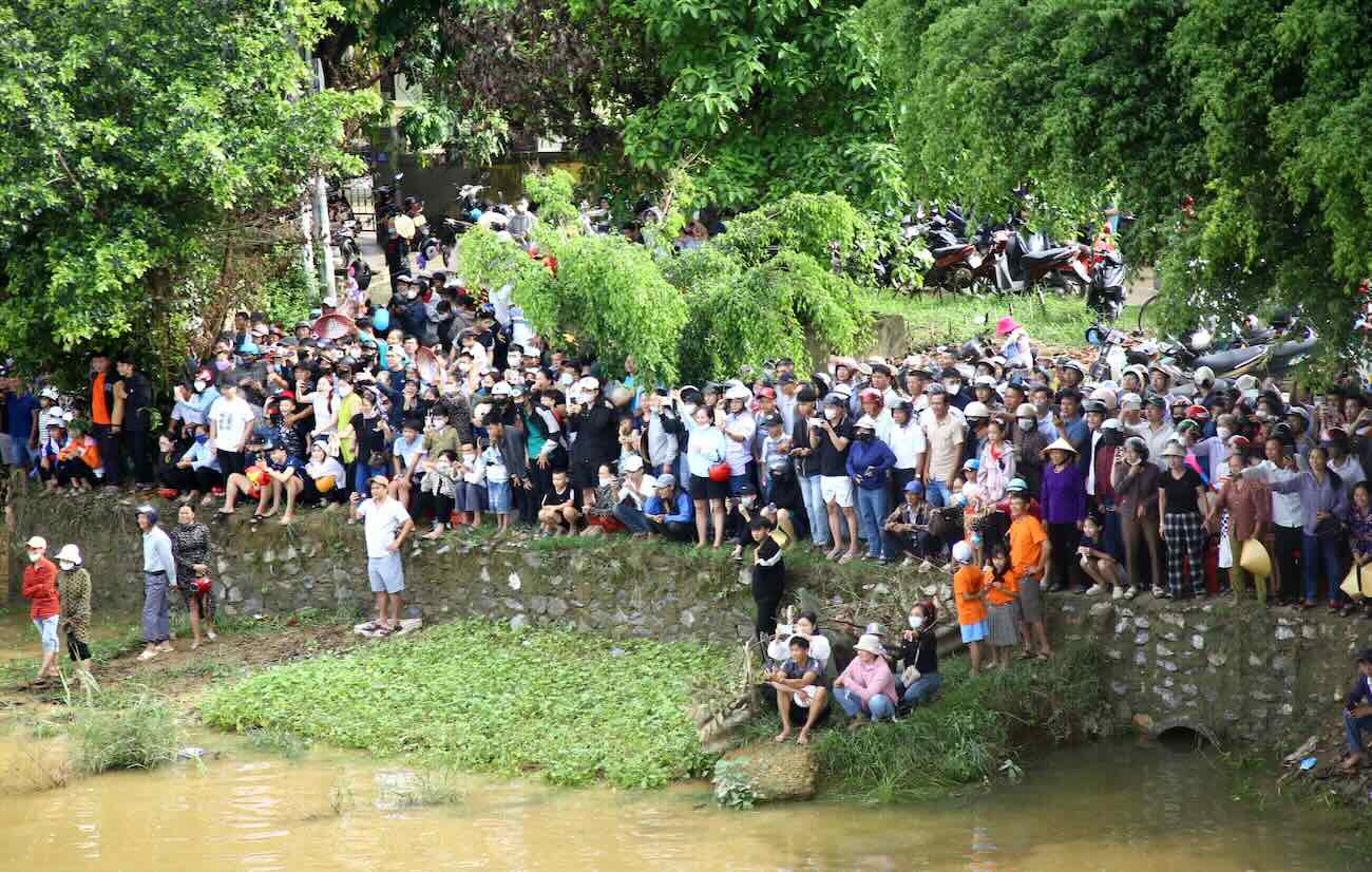 Residentes y turistas de pie junto a las 2 orillas del rio Kien Giang en Quang Tri viendo carreras de botes durante el Dia Nacional. Foto: Sang Hien