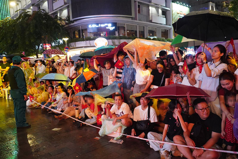 Voi o, ao mua, nguoi dan TPHCM van nan lai de theo doi cac hoat dong. Anh: Anh Tu