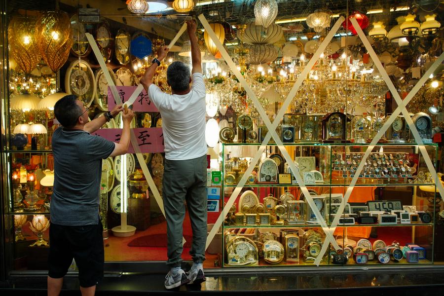 Nhan vien dan bang dinh len kinh cua mot cua hang o Hong Kong (Trung Quoc) ngay 22.9. Anh: Xinhua