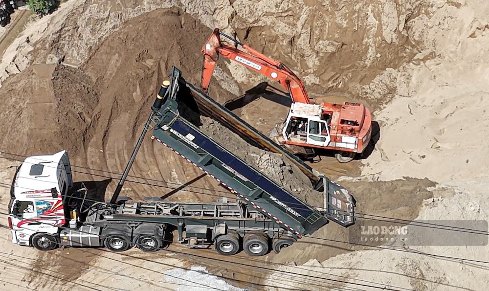 Sau khi mất nhiều phút để lùi, chiếc xe bắt đầu xả cát xuống bãi, tiếng động cơ gây náo loạn cả khu phố. Ảnh: PV