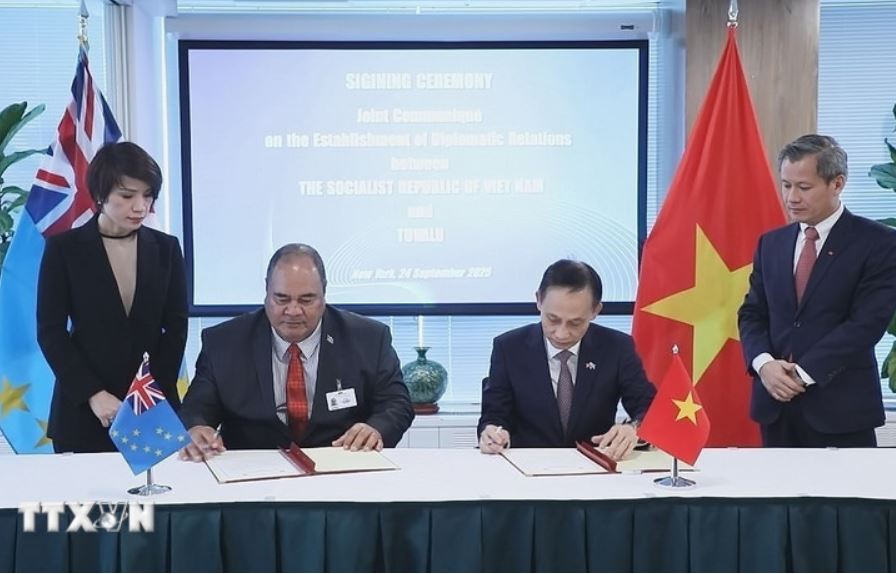 Le ministre par interim des Affaires etrangeres Le Hoai Trung et le ministre des Affaires etrangeres du Travail et du Commerce Tuvalu Paulson Panapa signent un communique commun etablissant des relations diplomatiques entre les deux pays. Photo : TTXVN