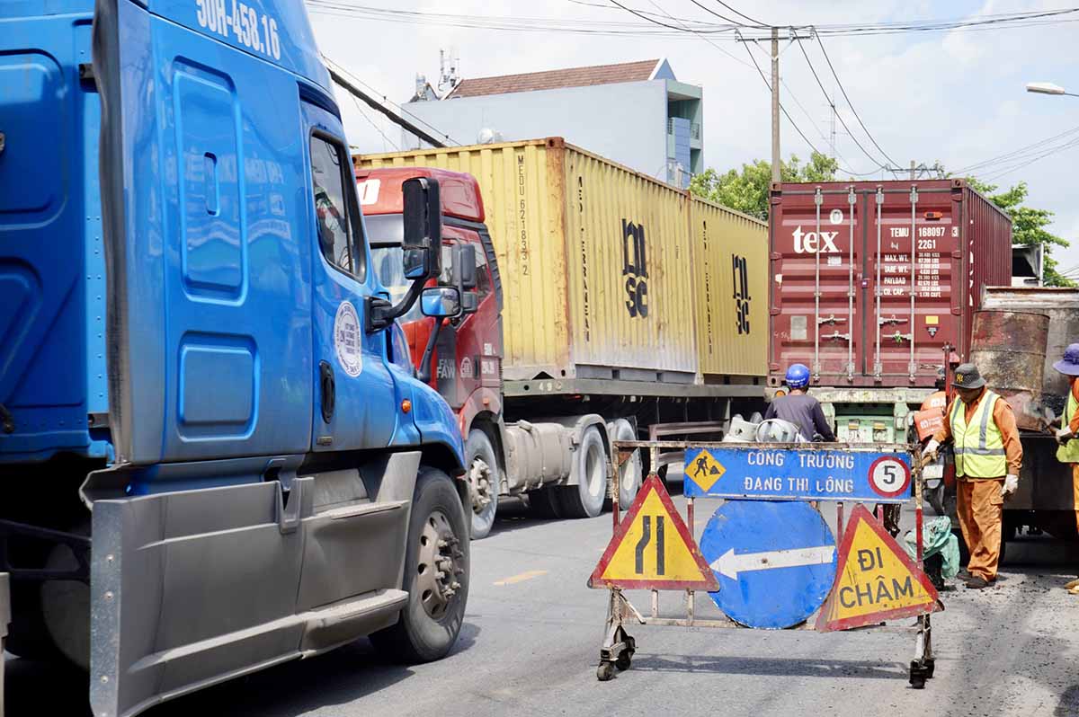 Nguoi di xe may len loi giua khoang trong chat hep giua cac xe container noi duoi nhau.