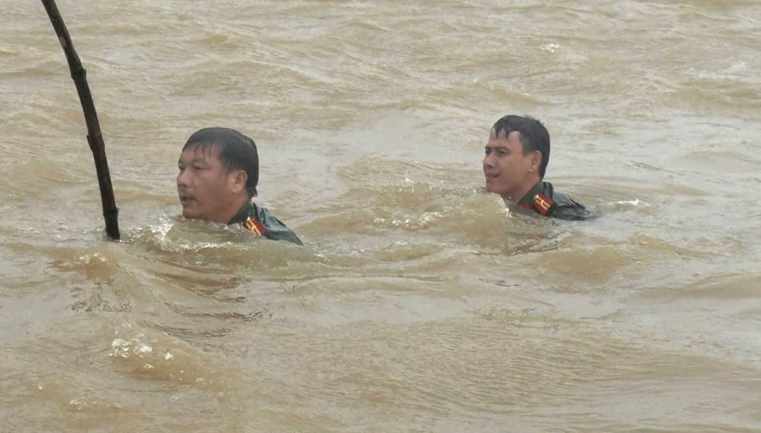 Two officers of Nam Cua Viet Commune Police wade through floodwaters to find a car swept away by floodwaters. Photo: Nam Cua Viet Commune Police