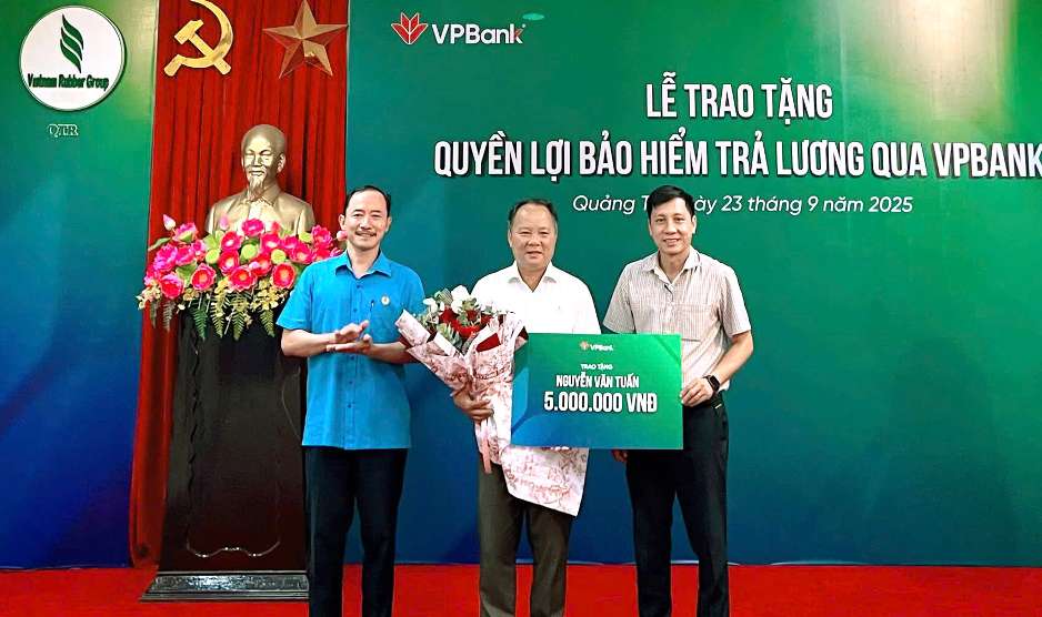 Dai dien Lien doan Lao dong (ben trai) va dai dien cong ty Cao Su Quang Tri (ben phai) trao bao hiem cho nguoi lao dong. Anh: VPBank