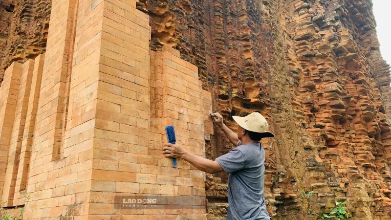 Hien tuong muoi hoa tren gach trung tu thap Cham Khuong My duoc xu ly tam thoi bang phuong phap cao rua thu cong. Anh: Nguyen Hoang