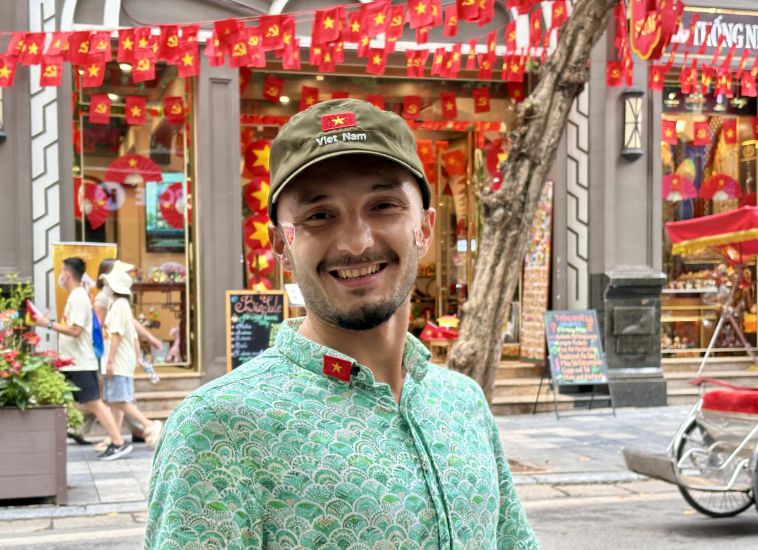 Spanish male tourist wears a red star-engraved hat and a Vietnamese flag while watching the 80th Anniversary of National Day on September 2 with people in Hanoi. Photo: Y Yen