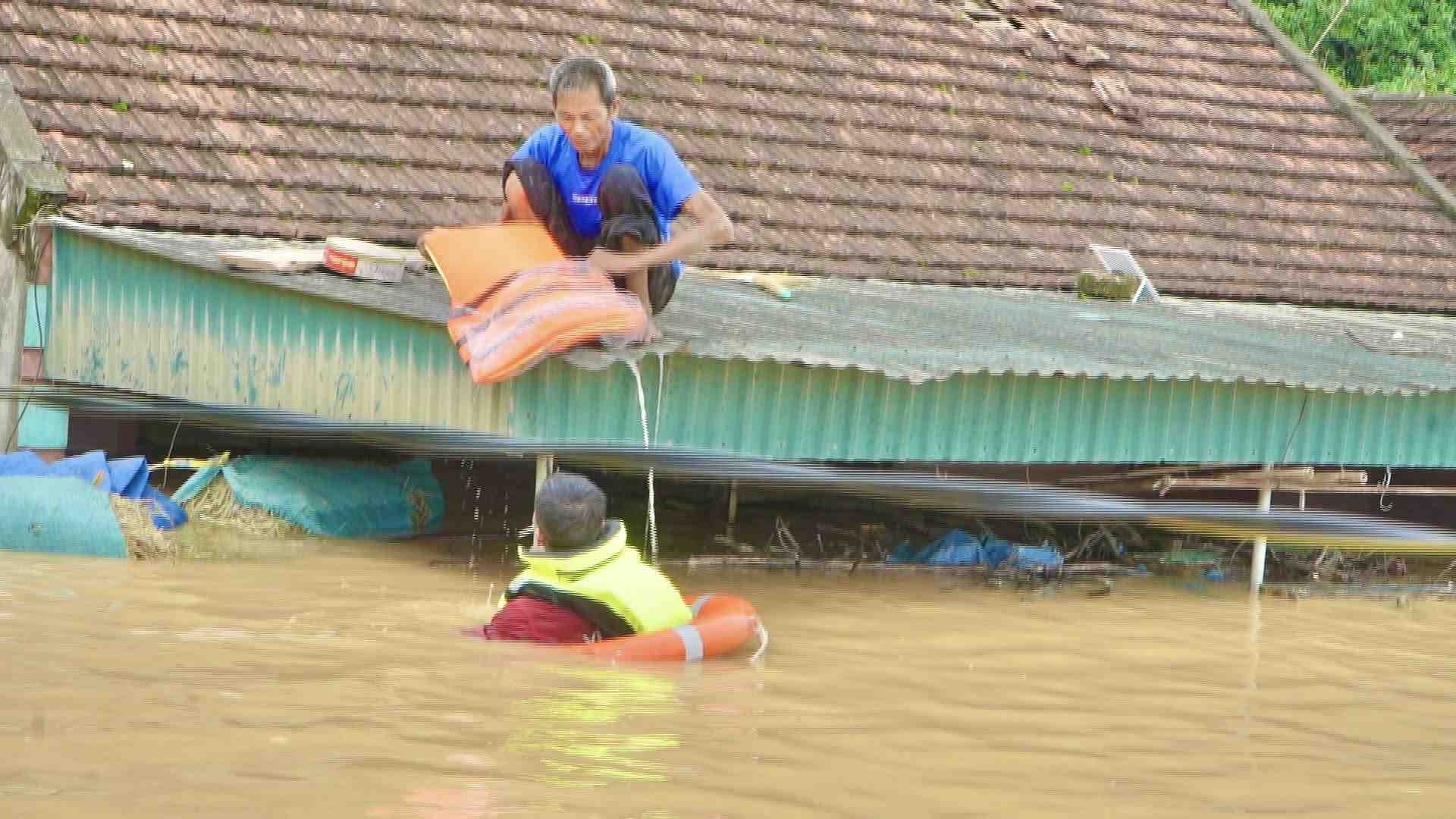 Nuoc lu dang len qua nhanh, mot nguoi dan xa Tan Ky phai treo len noc nha nho cuu ho. Anh: Ngoc Anh