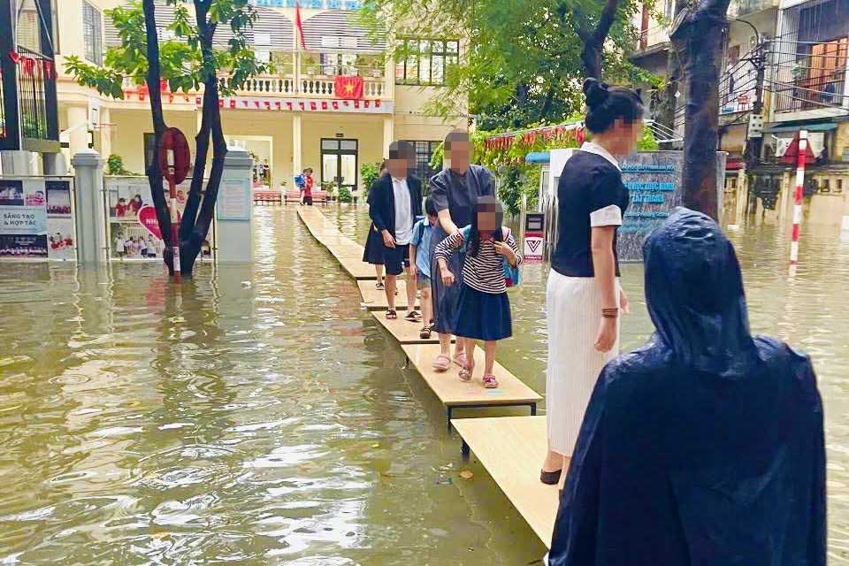 La escuela secundaria y preparatoria Nguyen Tat Thanh (Hanoi) coloca mesas en un camino para que los estudiantes no tengan que deslizarse por el agua para irse a casa despues de la escuela. Foto: Proporcionada por los padres