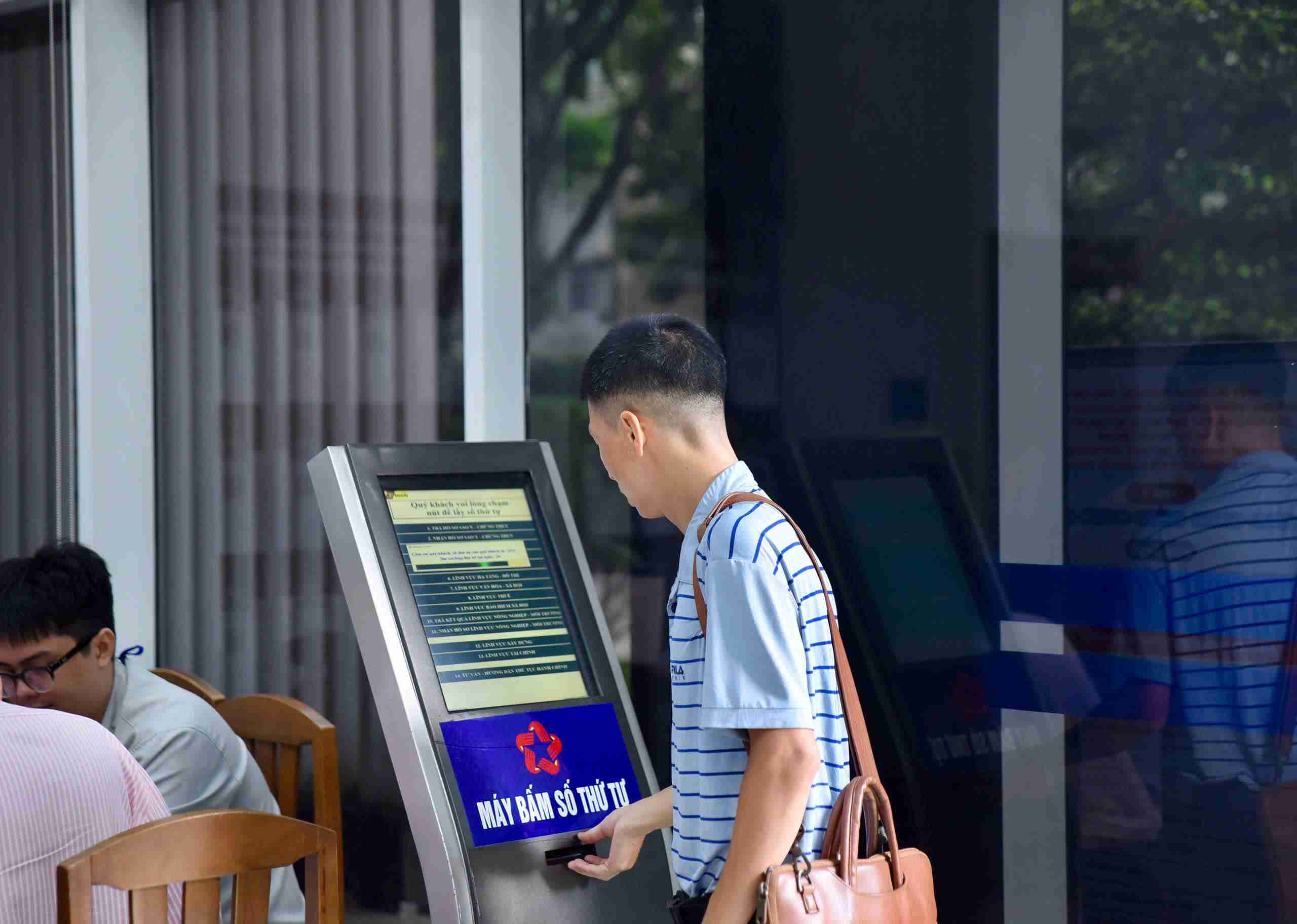Mot nguoi dan den boc so thu tu tren bang dien tu de lam thu tuc. Anh: Minh Tam