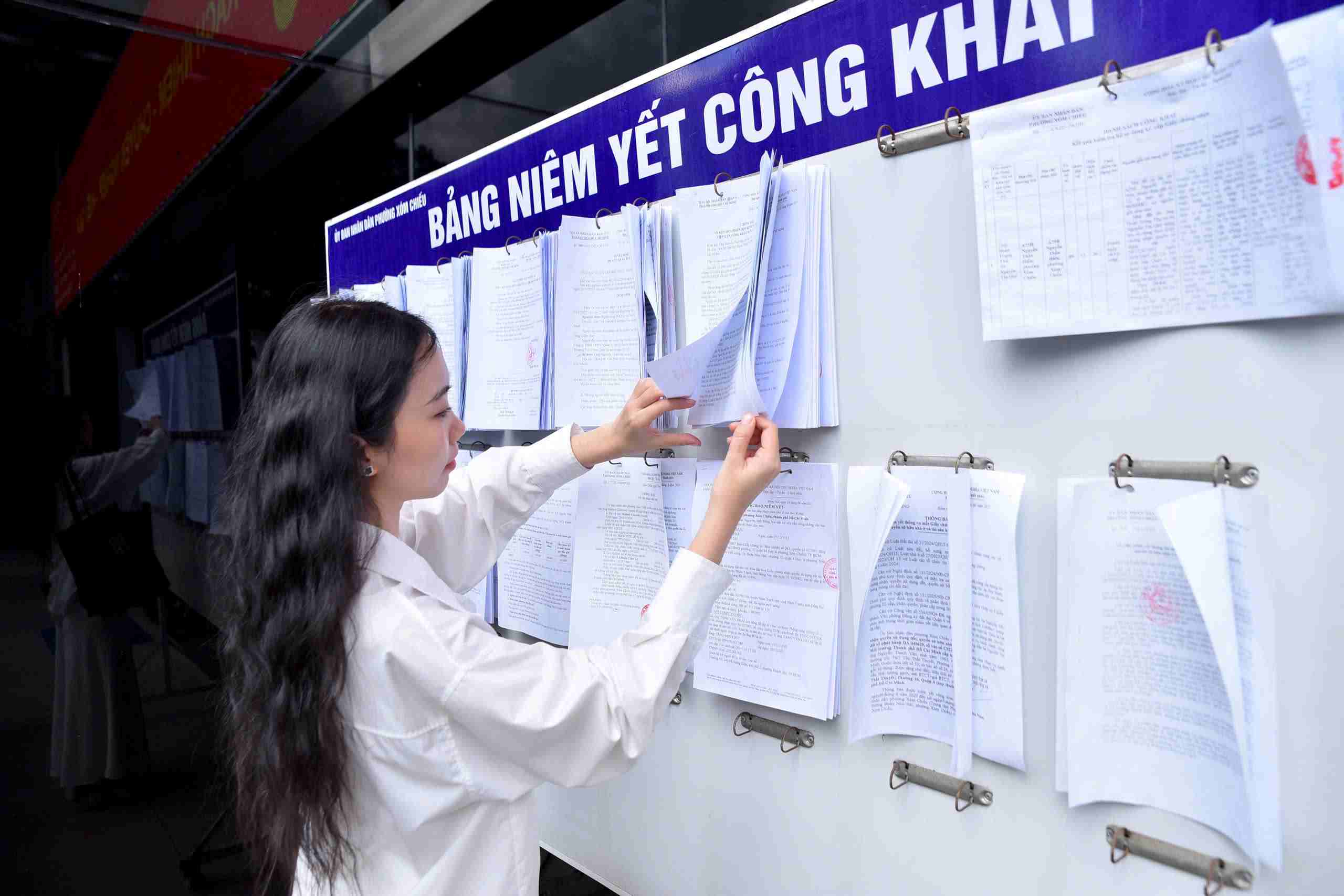 Nguoi dan dang tim hieu thong tin duoc cong khai tren bang niem yet cua phuong Xom Chieu. Anh: Minh Tam