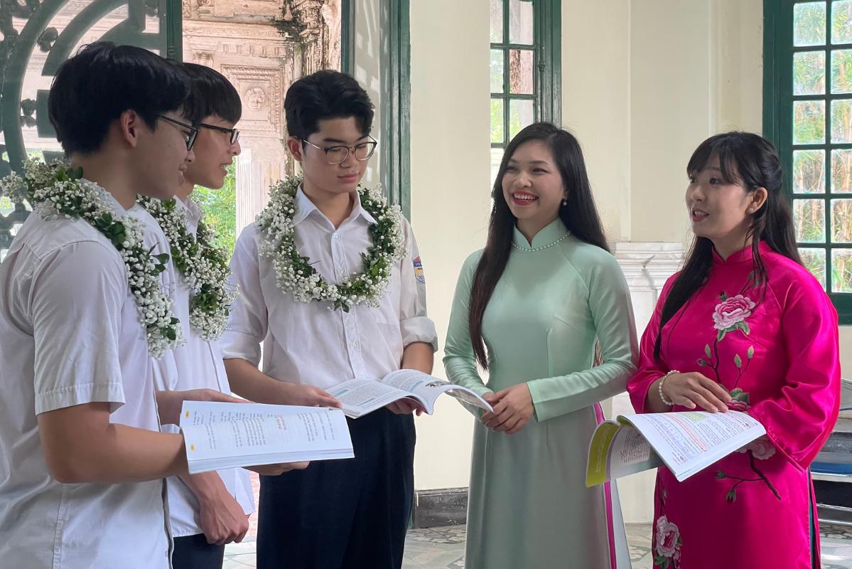 Co Nguyen Thi Thanh Tam (ao dai xanh) va co Nguyen Thi Giang (ao dai hong) chao don 3 cuu hoc sinh la nhung thu khoa, a khoa trong ky thi tot nghiep THPT nam 2025. Anh: Thanh Binh
