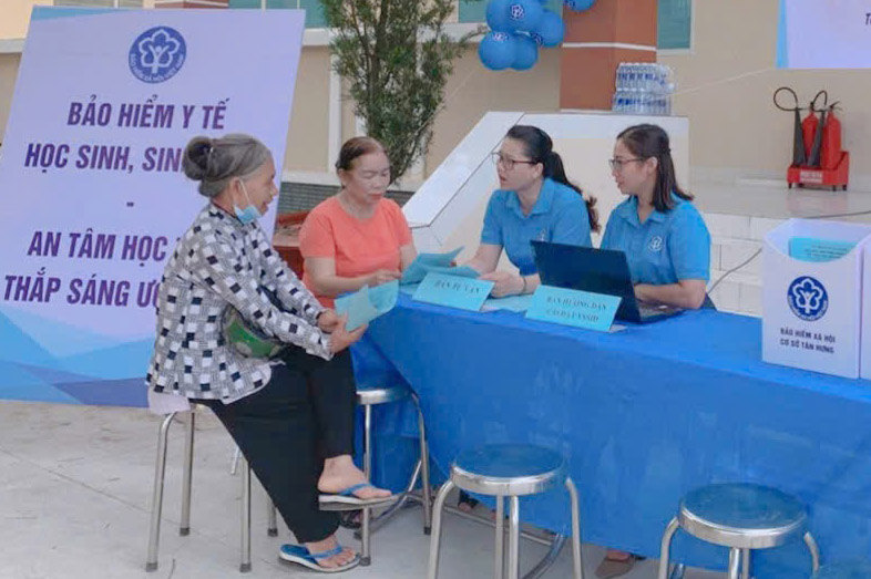 Tan Hung 기초 사회 보험 공무원이 학부모에게 건강 보험 혜택을 홍보하고 있습니다. 사진: Tay Ninh 지방 사회 보험
