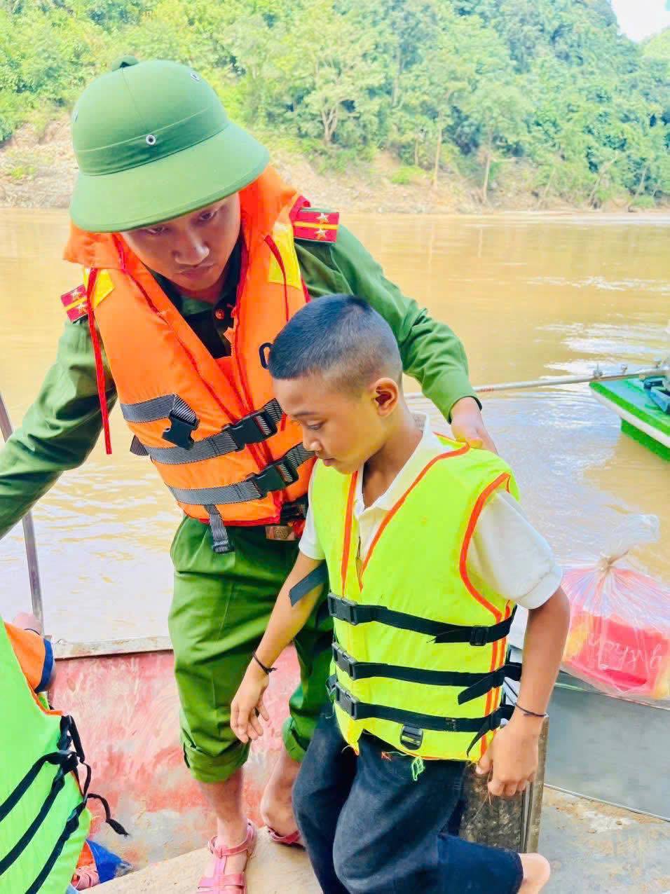 Cac em hoc sinh duoc can bo cong an xa ho tro mac ao phao truoc khi len thuyen. Anh: Ngoc Anh