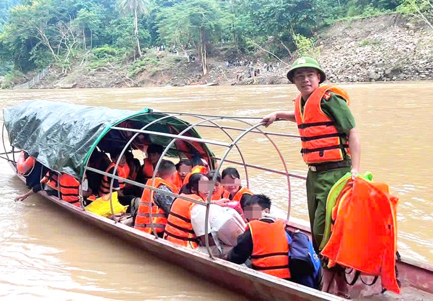 El teniente primero Nguyen Van Hung jefe de policia de la comuna de Luong Minh (Nghe An) ayuda a llevar a los niños pequeños al rio a la escuela de forma segura. Foto: Ngoc Anh