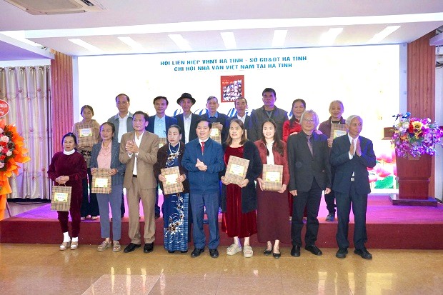 Giam doc So GDDT Ha Tinh Bui Nhan Sam (dung giua) va Chu tich Hoi Lien hiep Van hoc Nghe thuat Ha Tinh Tran Nam Phong, cung nha tho Le Van Vy trao qua va sach cho than nhan cac gia dinh nha giao liet si. Anh: Linh Chau.
