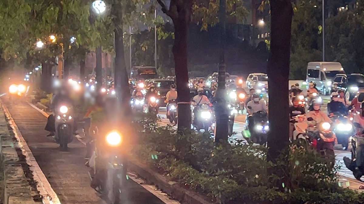 Crowds of motorbikes climbing onto sidewalks, going into bicycle lanes during peak hours in Ho Chi Minh City.