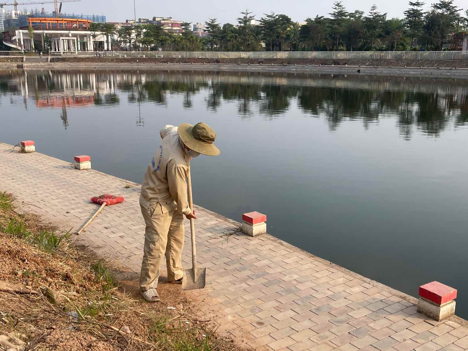 Cong nhan thu gom dat cat, lam sach khu vuc via he ven ho dieu hoa. Anh: Khanh An