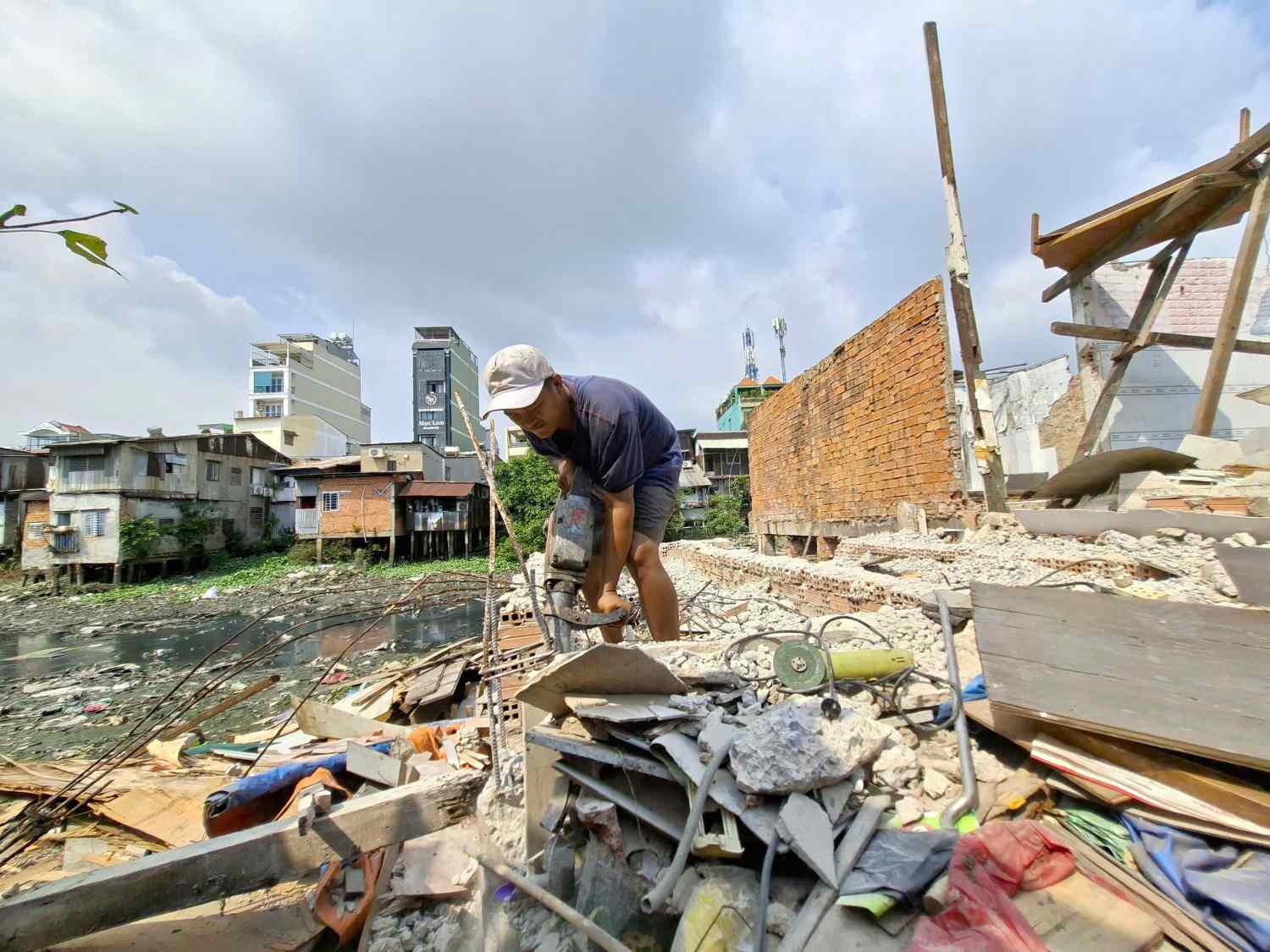 People in Ho Chi Minh City use drills to dismantle the foundation of a house along Xuyen Tam canal. Photo: Minh Quan