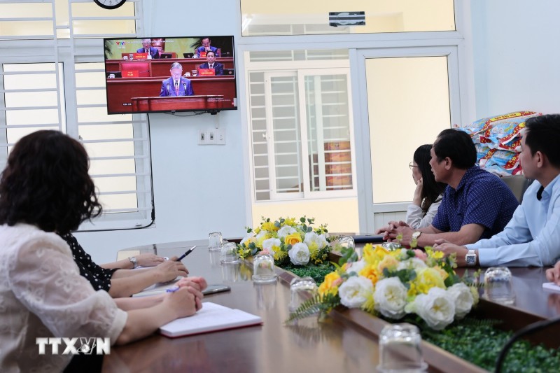 Nguoi dan, dang vien thanh pho Da Nang theo doi dong chi Tong Bi thu To Lam trinh bay Bao cao cua Ban Chap hanh Trung uong khoa XIII ve cac van kien trinh Dai hoi XIV cua Dang tai phien Khai mac Dai hoi. Anh: Xuan Quy/TTXVN 