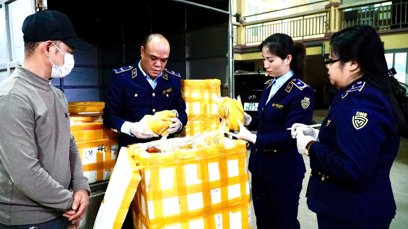 Market Management forces coordinate to check the legs of bone-removing chickens and salted chickens for violations. Photo: QLTT