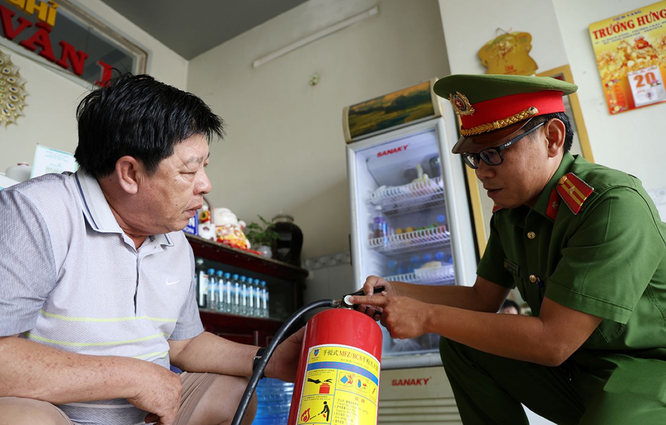 Cong an phuong Chau Doc huong dan chu nha nghi cach su dung binh chua chay. Anh: Vu Tien