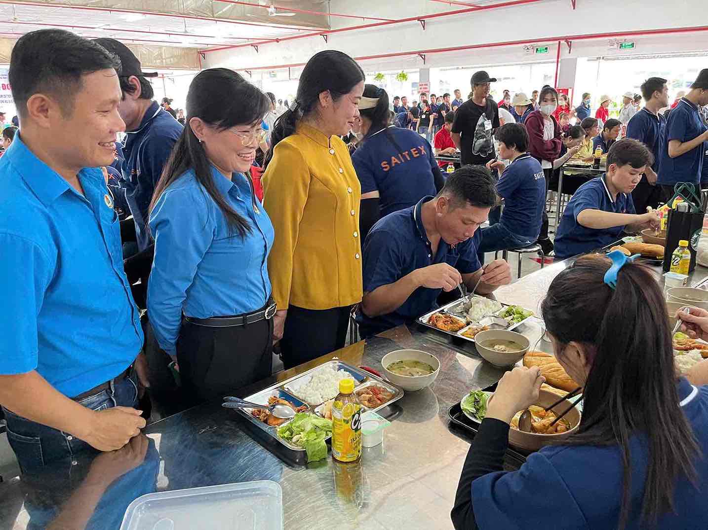 M. Le Van Binh - President du syndicat de base de la societe a responsabilite limitee Saitex International Dong Nai (a l'extreme gauche) - s'occupe du repas syndical pour les travailleurs. Photo: HAC