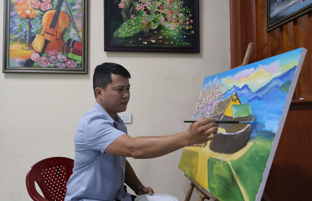 Village chief Cao Thanh Nam next to a painting being created. Photo: Thanh Trung.