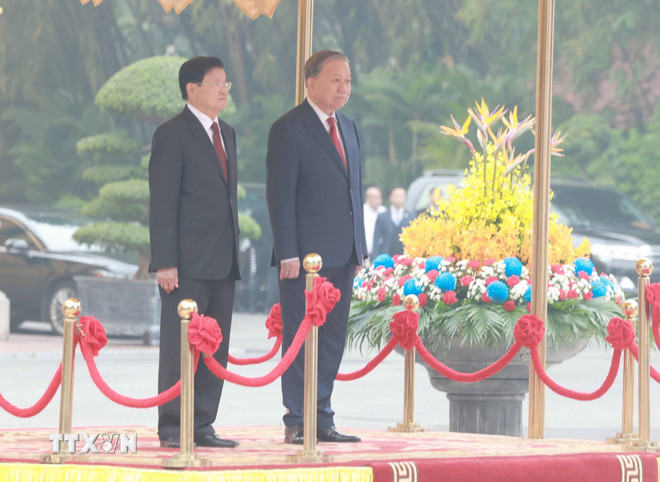 Tong Bi thu To Lam va Tong Bi thu, Chu tich nuoc Lao Thongloun Sisoulith tren buc danh du, thuc hien nghi thuc chao co. Anh: TTXVN