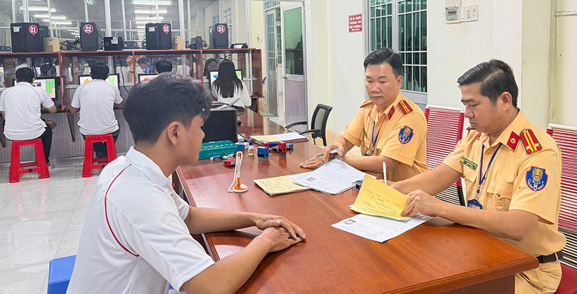 Officers of the Traffic Police Department, Ca Mau Provincial Police guide citizens to complete dossiers to participate in the GPLX test. Photo: Huu De.