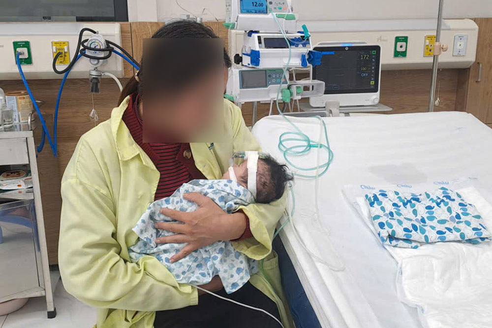 Weak mother after a stroke still takes care of her 2-month-old baby day and night in the recovery room. Photo: NVCC