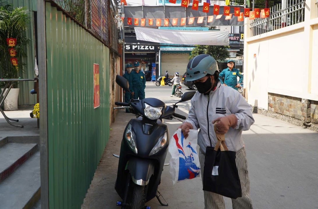 Chị Kim Chi mang cơm đến trường cho con sau khi trường tạm dừng ăn bán trú. Ảnh: Chân Phúc