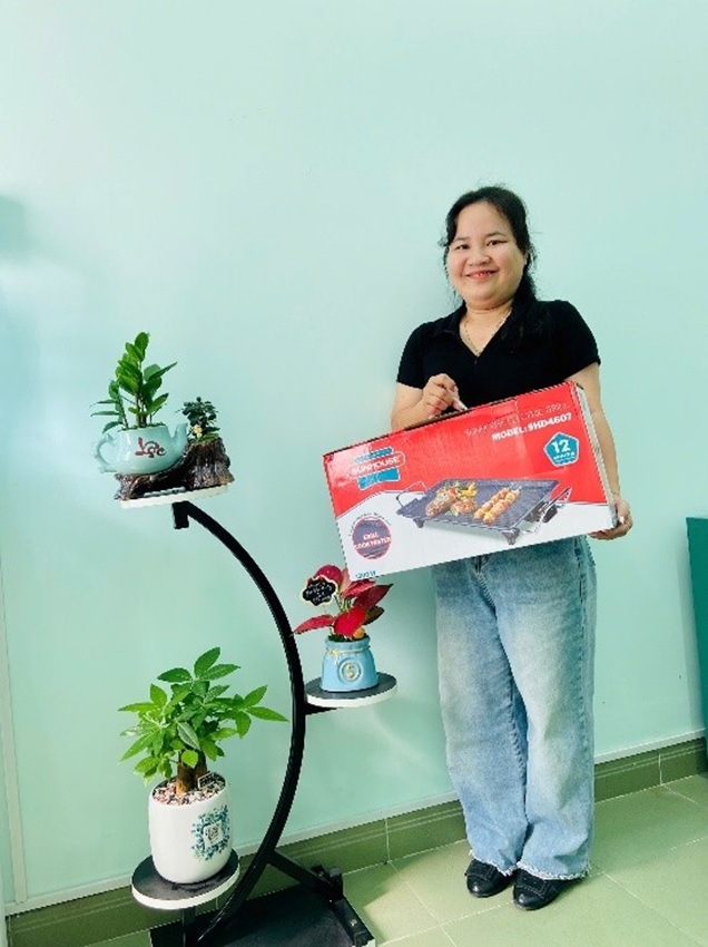 응우옌티홍하 씨 - 투안안 전력 회사 노동조합 조합원이 "노동조합 설날 시장 - 2026년 봄"에서 온라인 쇼핑 제품을 들고 있습니다. 사진: 뚜꾸옌