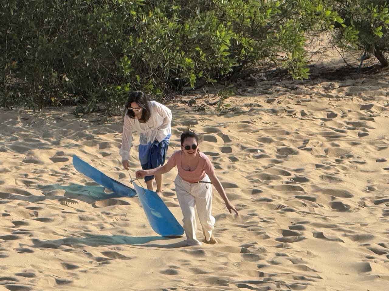 Du khách cầm ván leo lên đồi cát sau khi trượt xuống.