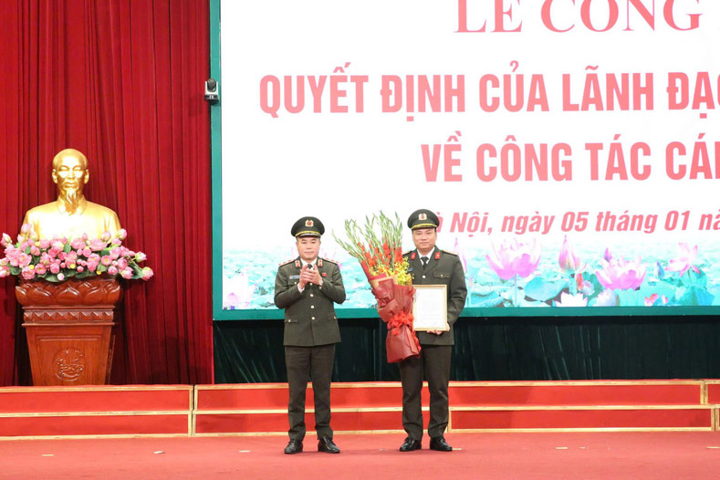 ハノイ市警察署長のグエン・タイン・トゥン中将が決定書を授与し、グエン・ティエン・ダット大佐(ハノイ市警察副署長)がハノイ市警察捜査機関長に任命されたことを祝う花束を贈呈。写真:ハノイ市警察