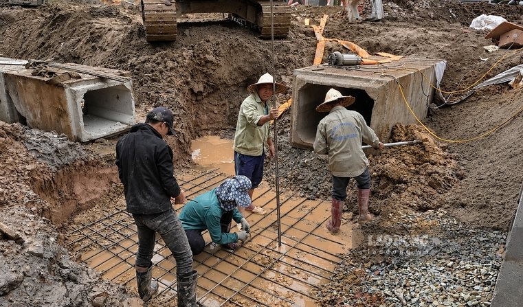 Công nhân phối hợp lắp đặt hệ thống cống thoát nước, thực hiện các hạng mục kỹ thuật của tuyến đường.