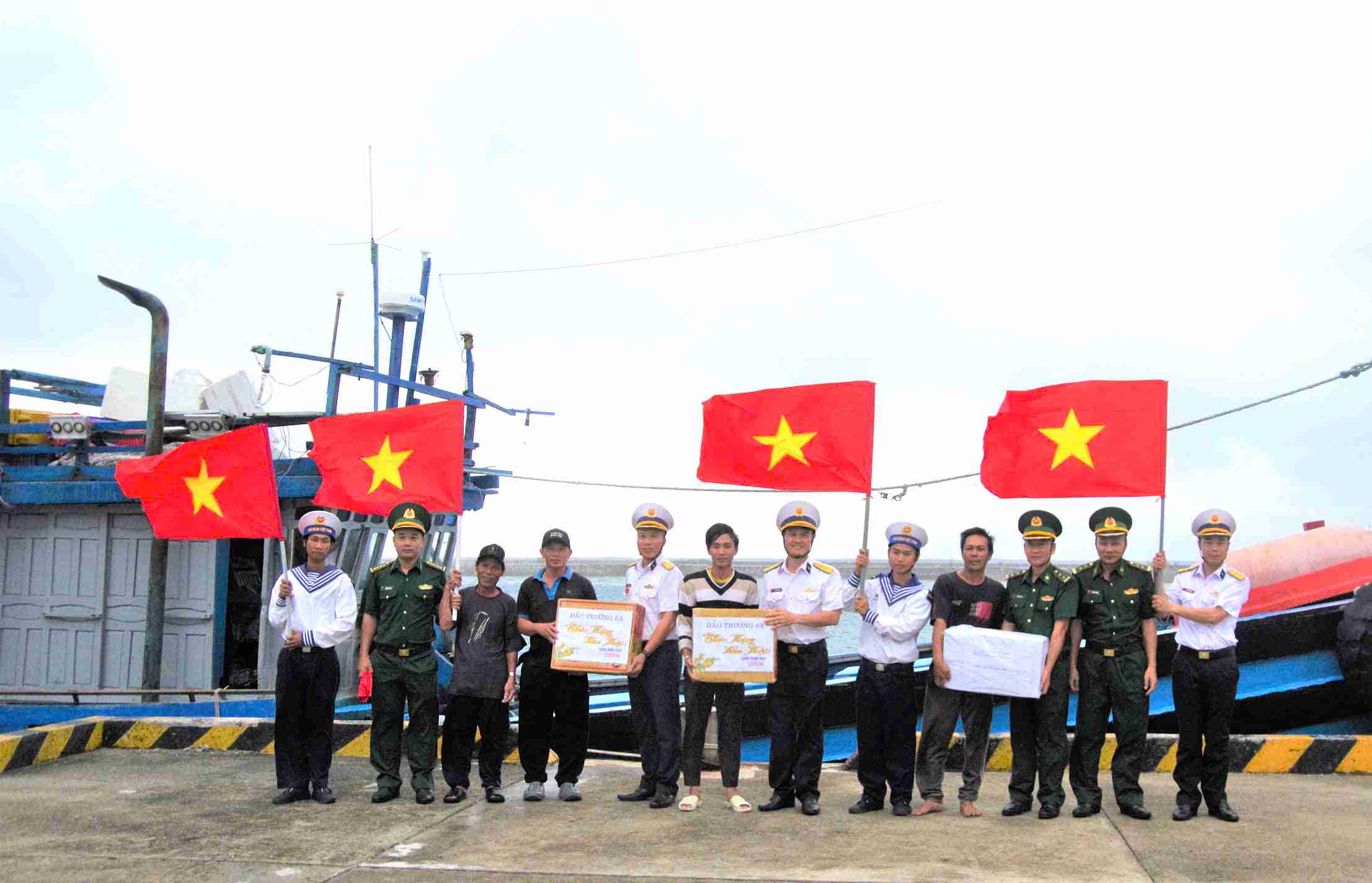 Officers and soldiers on Truong Sa Island give Tet gifts to fishermen on fishing boats entering for shelter. Photo: Binh Quy