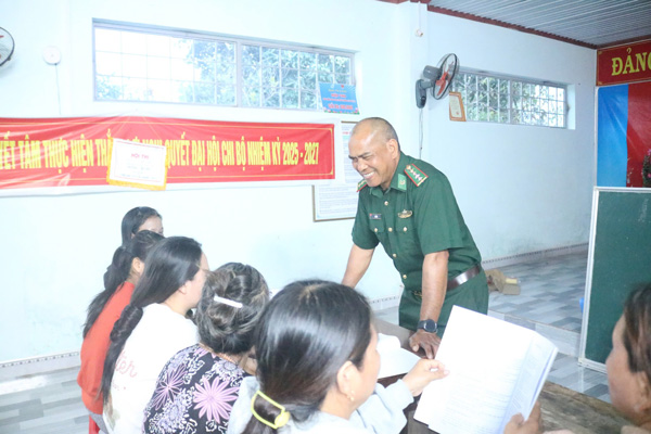 Captain A Bung - a green-uniformed soldier teaching literacy to class members, many of whom are over 50 years old. Photo: Thanh Tuan
