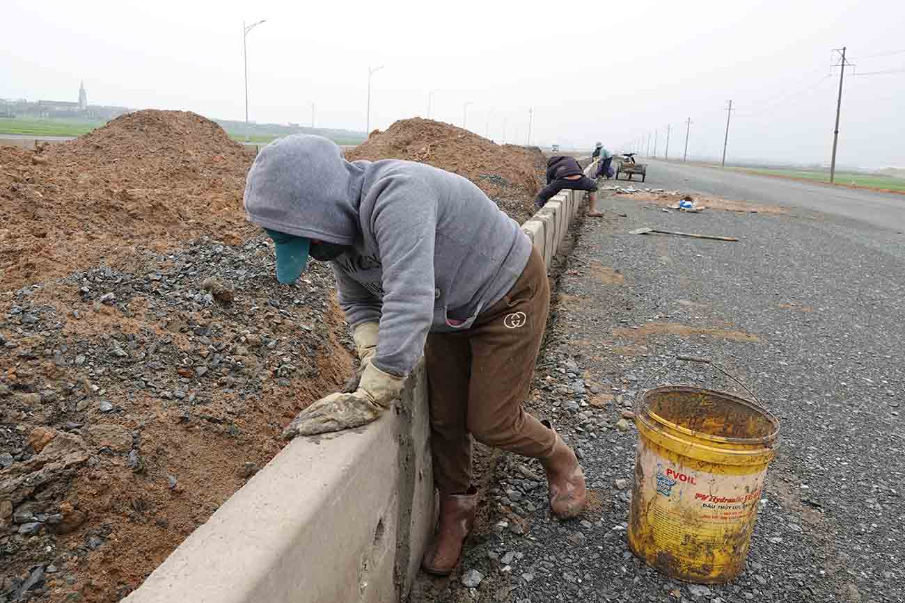 Chị Hoa đang trám xi măng gắn những tấm dải phân cách cứng lại với nhau tại công trường Dự án đường trục chính trung tâm nối Quốc lộ 1 đoạn tránh thị xã Kỳ Anh (cũ) đến cụm cảng nước sâu Vũng Áng - Sơn Dương. Ảnh: Trần Tuấn.