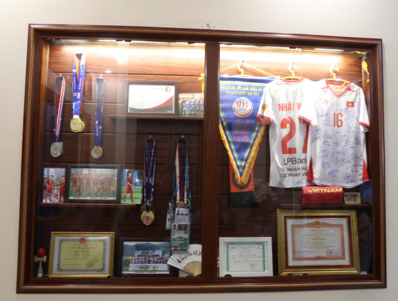 Mà Thu nâng niu từng tấm huy chương, bằng khen, áo thi đấu của con trai. Ảnh: Mai Hương