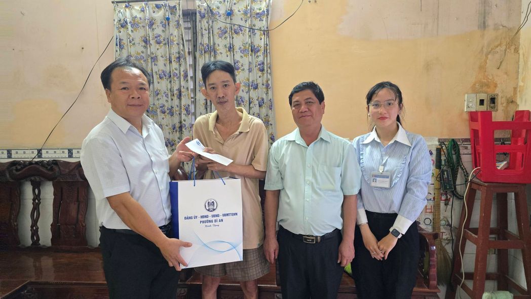 Ông Nguyễn Văn Đông - Bí thư Đảng ủy phường Dĩ An (bìa trái) thăm và tặng quà cho người dân khó khăn. Ảnh: Bạn đọc cung cấp