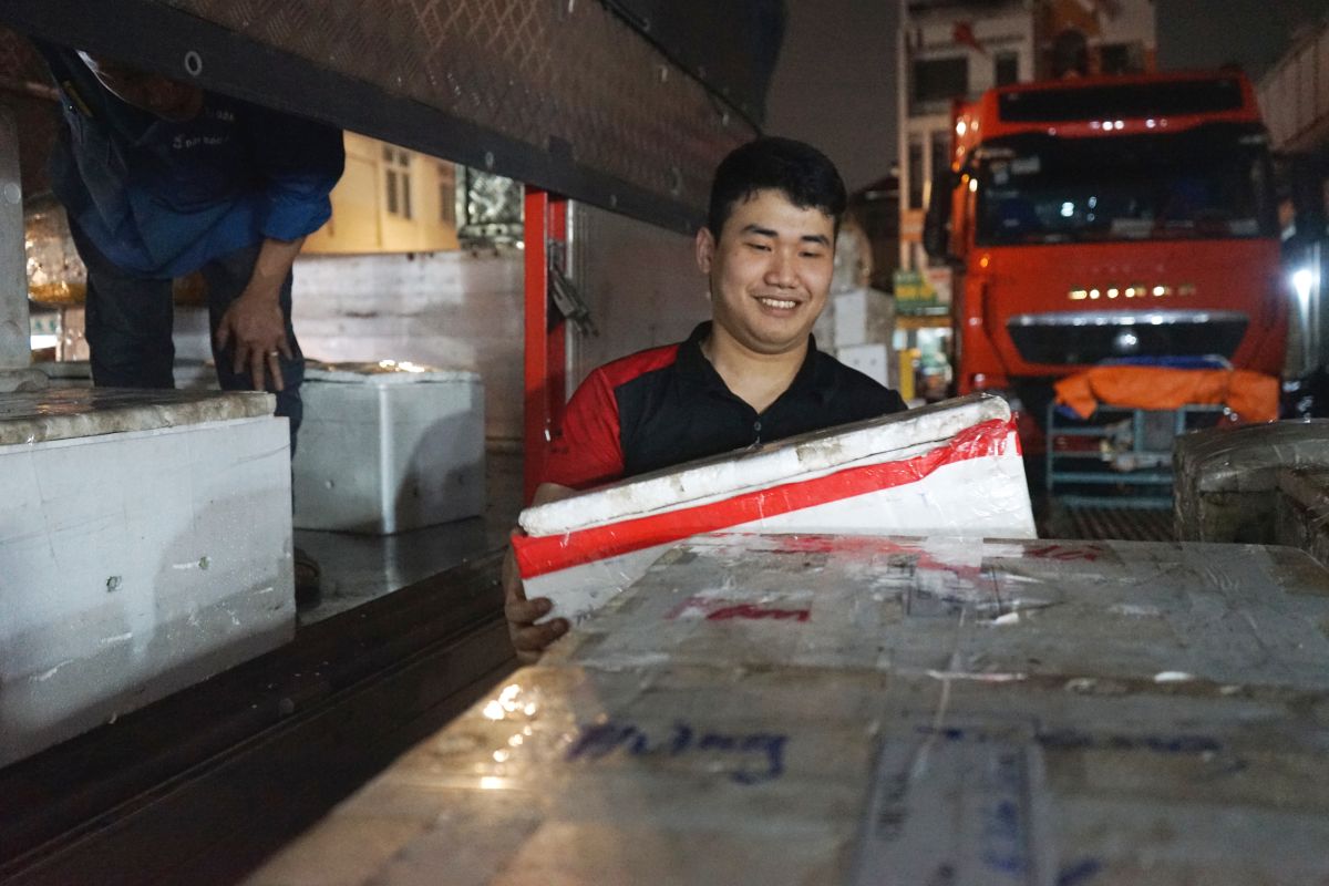 Anh Nguyễn Huy Vũ (người bốc vác thuê tại chợ) làm việc xuyên đêm tại chợ đầu mối. Ảnh: Quách Du