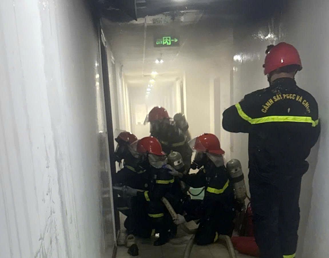 Los bomberos se esfuerzan por enfriar el apartamento del piso 16, donde ocurrió el incendio que mató a 2 personas. Foto: Phuong Linh