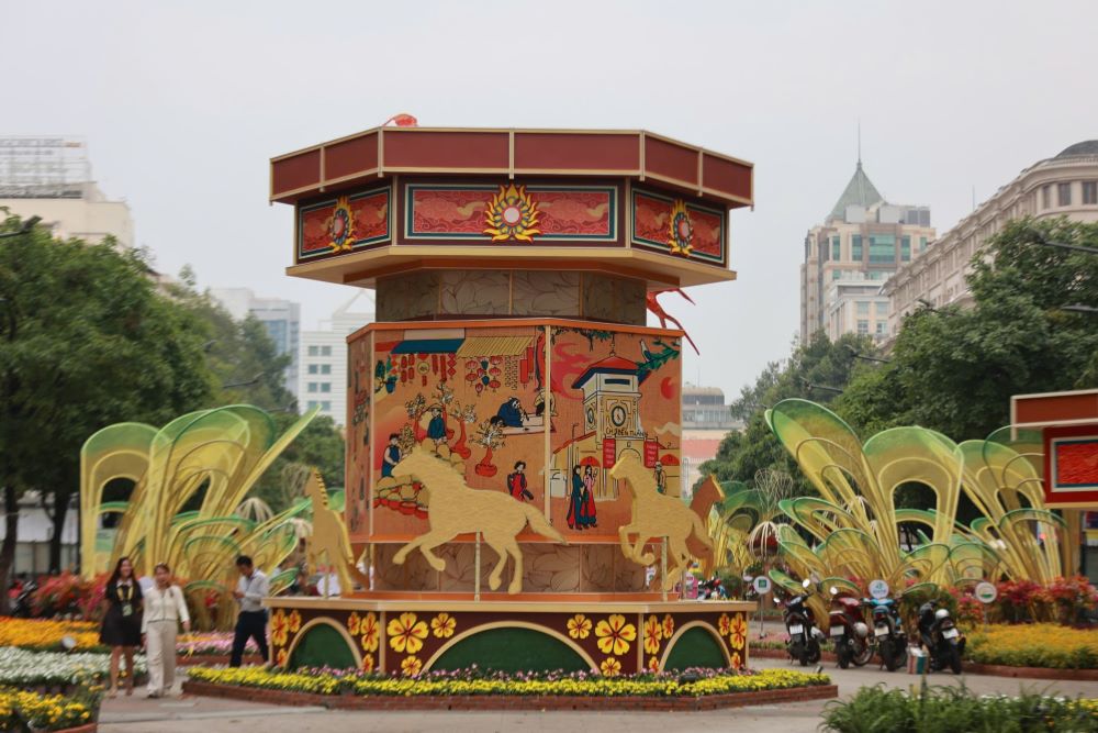 Ở đại cảnh “Rực rỡ miền ký ức”, chiếc đèn kéo quân cao hơn 6 m với trục xoay liên tục cũng đã vận hành thử, tái hiện sinh động khung cảnh dân gian ngày Tết. Cuối tuyến, đoạn giao Tôn Đức Thắng, công nhân vẫn miệt mài hoàn thiện các mảng hoa cho đại cảnh kết. Ảnh: Thái Bảo.