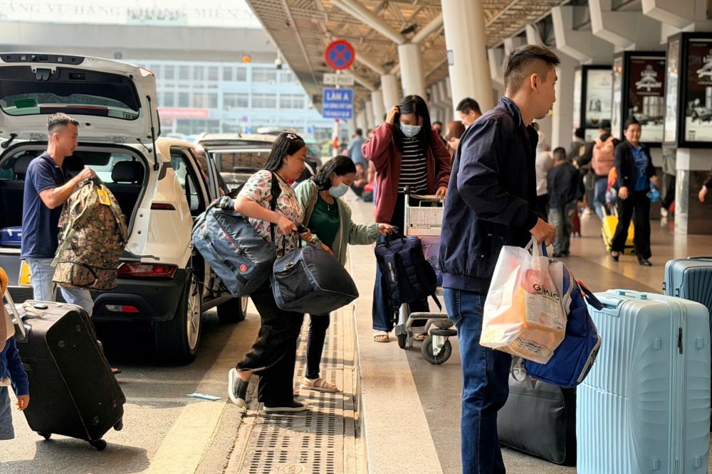 Hành khách lỉnh kỉnh hành lý, quà Tết nối đuôi nhau di chuyển vào nhà ga T1. Ảnh: Anh Tú